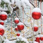 Fiocchi di neve sui plloncini rossi appesi ai rami di un abete